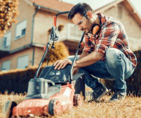 Man cleans the hand-push lawn mower Stock Photo 02