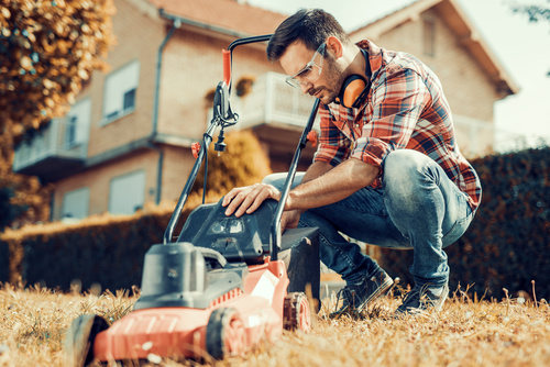 Man cleans the hand-push lawn mower Stock Photo 02