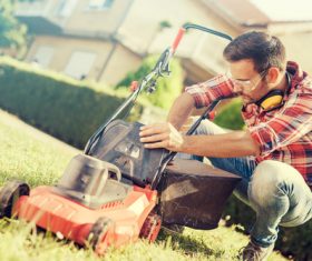 Man cleans the hand-push lawn mower Stock Photo 03