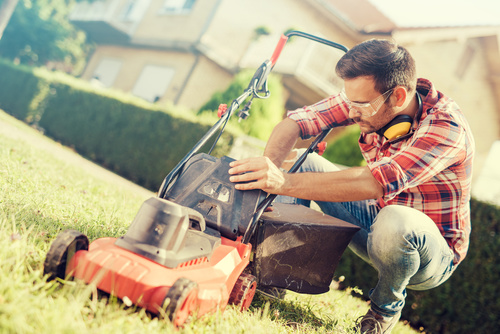 Man cleans the hand-push lawn mower Stock Photo 03