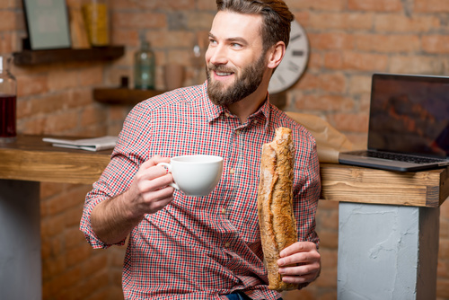 Man drinking coffee and eating bread Stock Photo