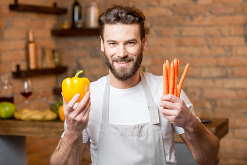 Man holding colorful peppers and carrots Stock Photo