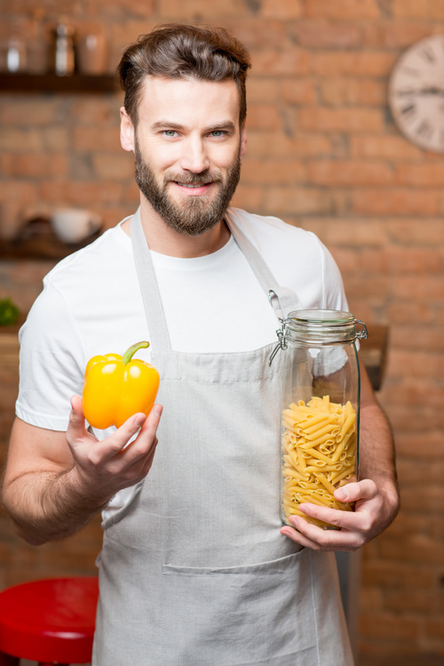 Man holding colorful peppers and spaghetti Stock Photo