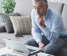 Man sitting on the couch looking at computer data Stock Photo