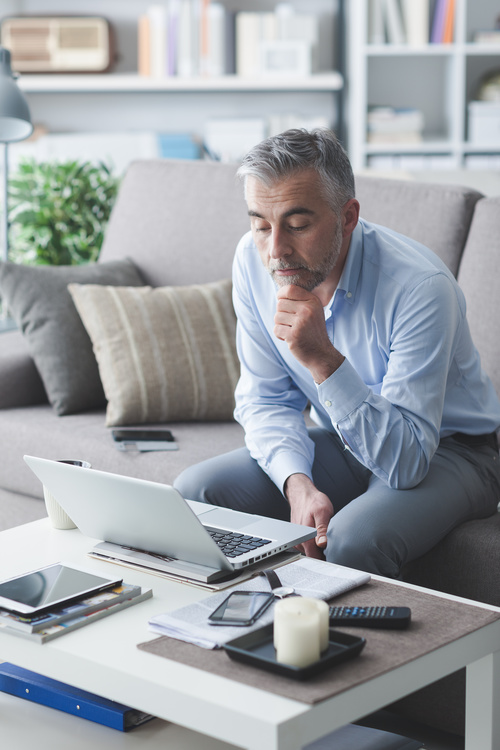 Man sitting on the couch looking at computer data Stock Photo