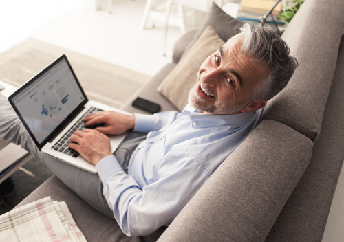 Man sitting on the couch surfing the internet Stock Photo