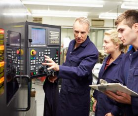 Old workers explain the control panel to young workers Stock Photo