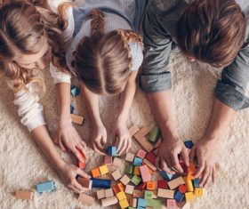 Parents build blocks with their daughter on the carpet Stock Photo