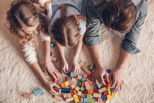 Parents build blocks with their daughter on the carpet Stock Photo