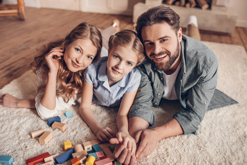 Parents play with their daughter on the carpet Stock Photo