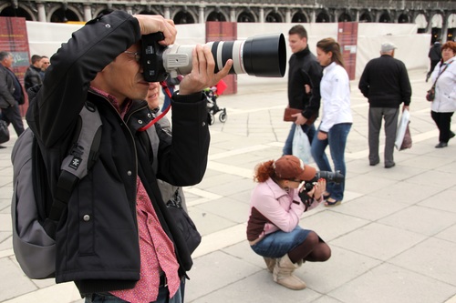 People who use a variety of cameras to take pictures on the street Stock Photo