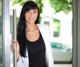 Smiling woman opening door Stock Photo