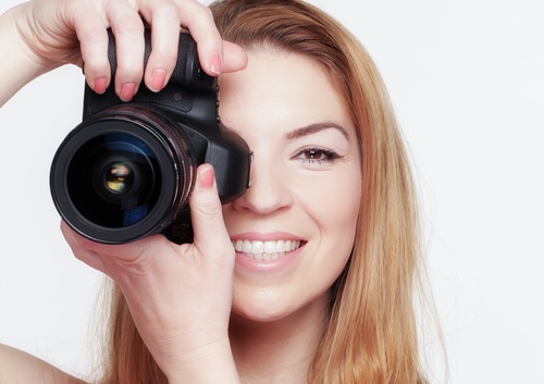 Smiling woman photographing with camera Stock Photo