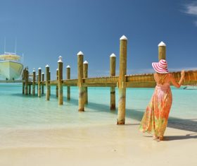 Stock Photo Woman standing next to the pier looking at the yacht
