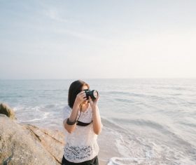 The woman holding the camera at the beach Stock Photo