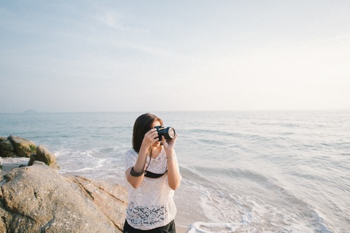 The woman holding the camera at the beach Stock Photo