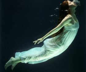 Woman diving under water with white dress Stock Photo