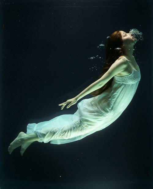Woman diving under water with white dress Stock Photo