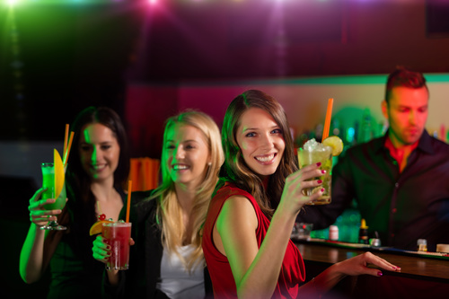 Woman drinking drink in front of nightclub bar Stock Photo