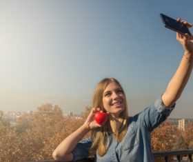Woman holding heart shaped selfie using mobile phone Stock Photo 02