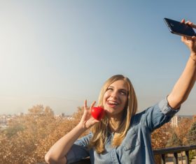 Woman holding heart shaped selfie using mobile phone Stock Photo 03