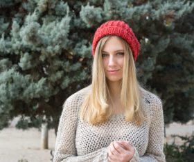 Woman in knit sweater standing in front of pine tree Stock Photo 02