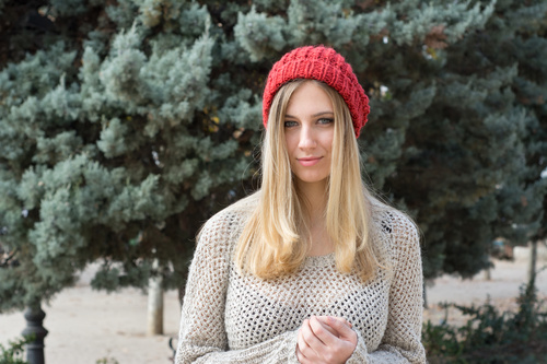 Woman in knit sweater standing in front of pine tree Stock Photo 02
