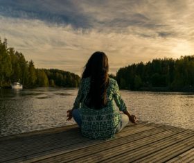 Woman sitting facing the lake cross-legged Stock Photo
