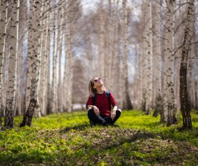 Woman sitting in birch forest Stock Photo
