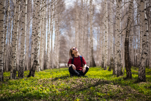 Woman sitting in birch forest Stock Photo