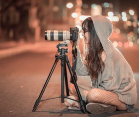 Woman sitting on the highway at night taking photos Stock Photo