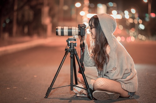Woman sitting on the highway at night taking photos Stock Photo