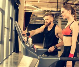 Woman standing on treadmill and coach adjusting treadmill Stock Photo