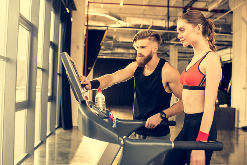 Woman standing on treadmill and coach adjusting treadmill Stock Photo