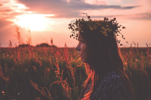 Young girl with flowers wreath at sunset Stock Photo