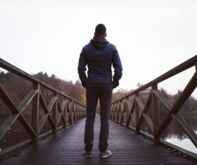 Back view of man standing on wooden bridge Stock Photo