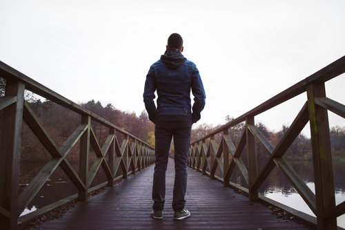 Back view of man standing on wooden bridge Stock Photo