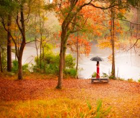 Beautiful autumn and pose woman sitting by the lake Stock Photo
