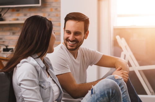 Cheerful Couple sitting on the floor chatting Stock Photo