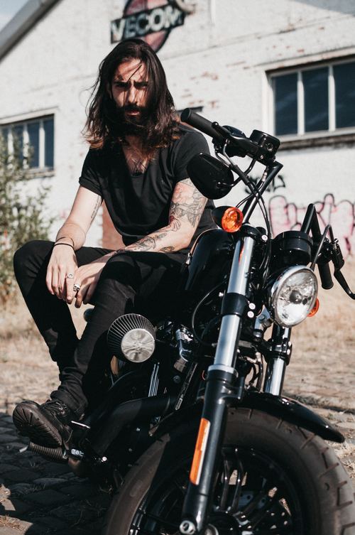 Long-haired man sitting on motorcycle Stock Photo free download