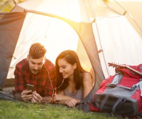 Lovers listening to music on the phone in camping tent Stock Photo
