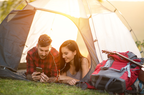 Lovers listening to music on the phone in camping tent Stock Photo
