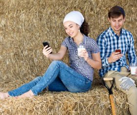 Male and female holding a glass of milk and playing with mobile phones Stock Photo