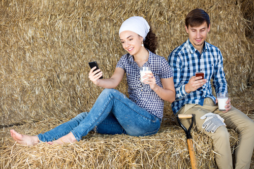 Male and female holding a glass of milk and playing with mobile phones Stock Photo