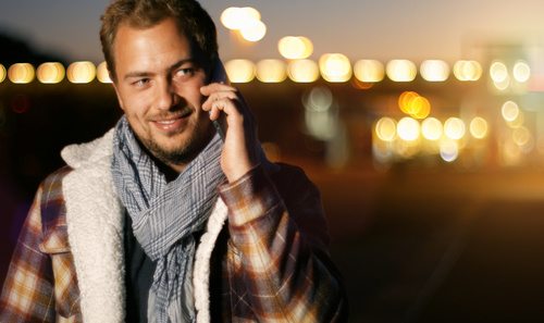 Man answering the phone and blurred lights behind him Stock Photo