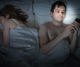 Man playing with mobile phone in bed Stock Photo
