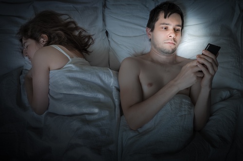 Man playing with mobile phone in bed Stock Photo