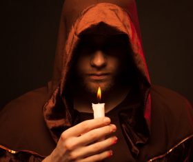 Man wearing cloak holding candle Stock Photo