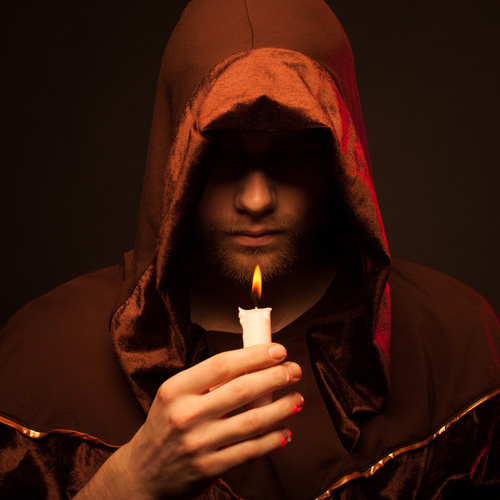 Man wearing cloak holding candle Stock Photo