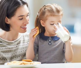 Mother looking at daughter eating breakfast Stock Photo